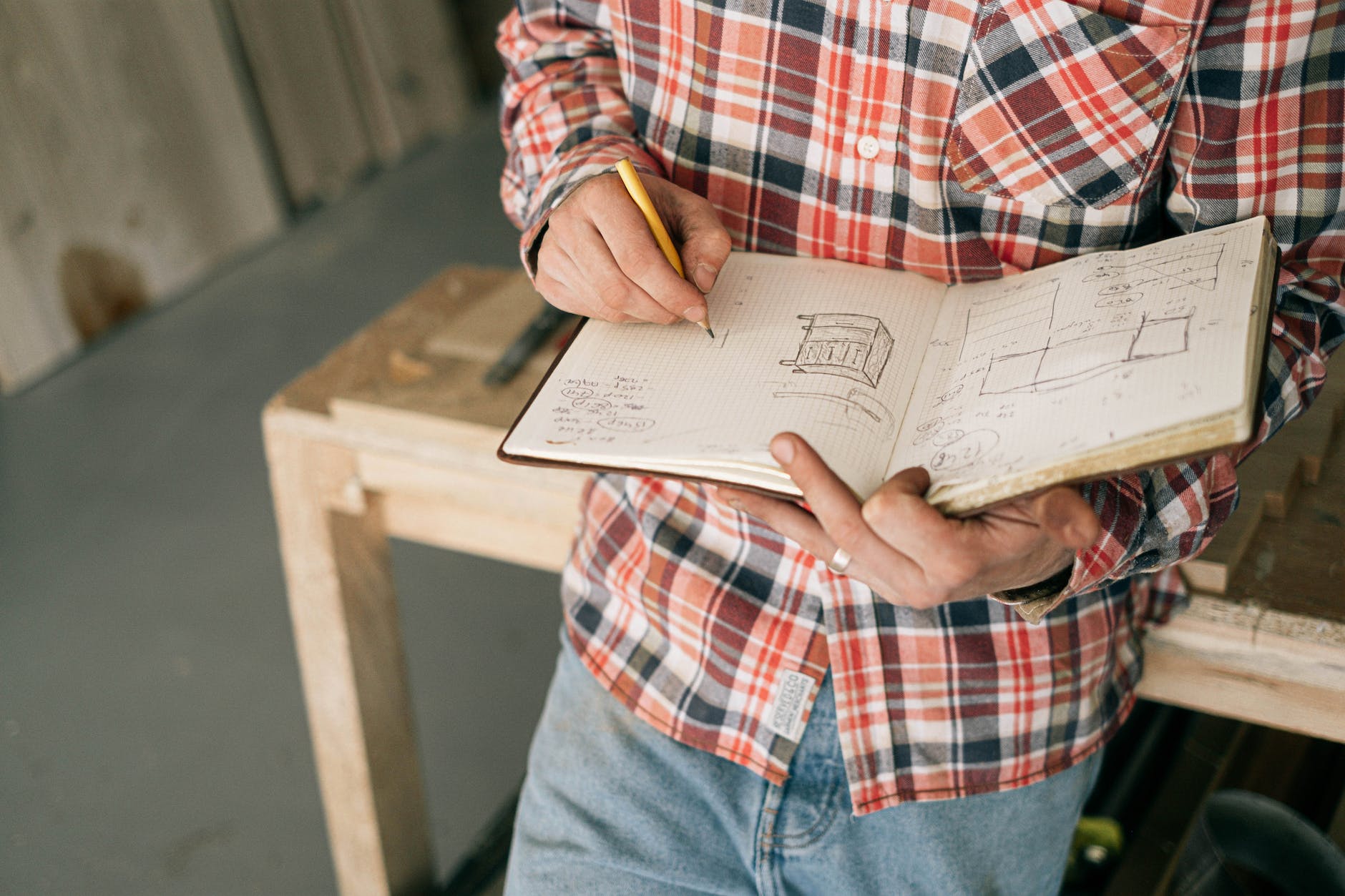 crop carpenter drawing furniture sketches in notebook